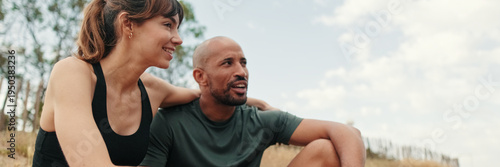 Canvastavla Side view of multi-ethnic male and female athletes sitting on a hill under trees, hugging, talking and supporting each other