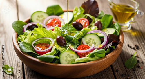 Pouring olive oil on fresh vegetable salad in a wooden bowl on rustic table