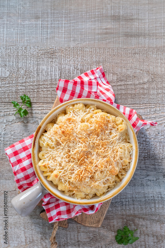Warm baked macaroni and cheese served on a wooden table with checkered napkin