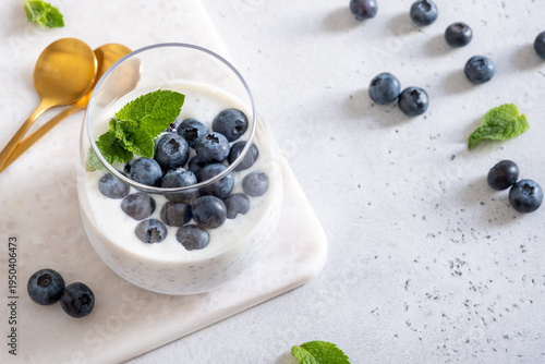 Fresh Yogurt With Blueberries and Mint Served in a Glass on a Table With Golden Spoons