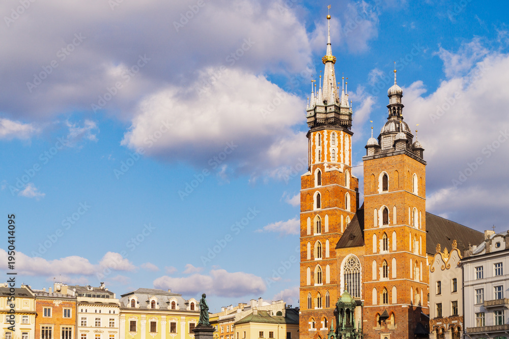 Fototapeta premium St. Mary's Basilica stands tall in Krakow's main square under a clear blue sky on a sunny day