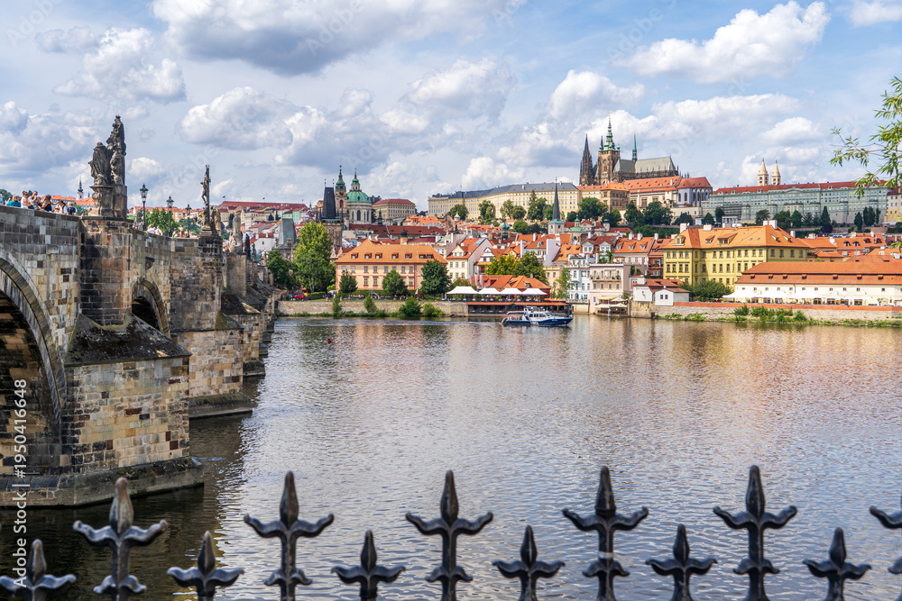 Obraz premium Panoramic view of Prague historic Mala Strana district, Prague Castle, the Vltava River and Charles Bridge in summer under a blue sky with white clouds, Prague, Czech Republic 
