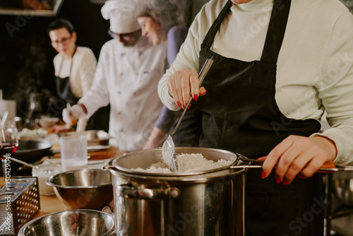 Foto Middle aged Caucasian woman straining cooked rice over pot in foreground, multie