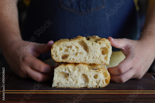 Quadro su tela Close up of a fluffy focaccia bread with a crispy, golden crust and hands in the