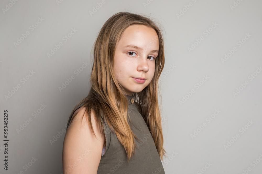 Fototapeta premium Smart child girl with brown hair looking at camera, portrait. Young girl 10 years old