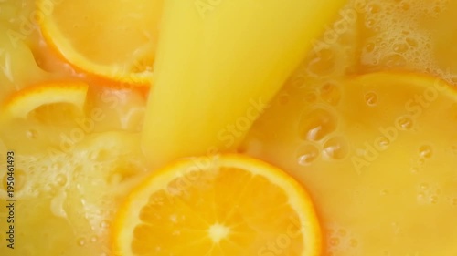 Vibrant orange juice stream drenching organic fruit, slow motion.