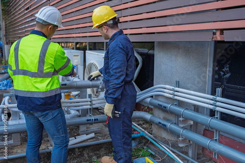 Foto Two professional engineers inspecting industrial air conditioning system outside