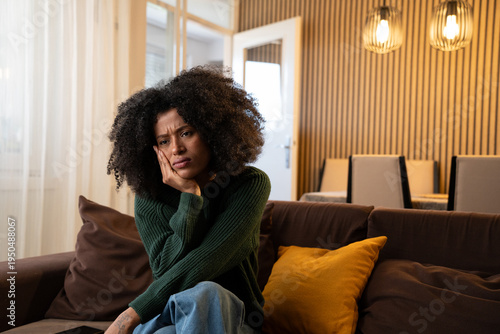 Young attractive black woman sitting at home living room couch feeling sad tired and worried suffering depression in mental health, problems and broken heart concept