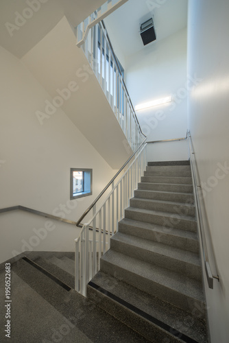 Modern hospital corridor interior with elevators and emergency exit signs.