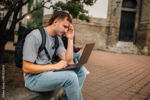 Cuadro en lienzo Pensive student working on laptop outside university building