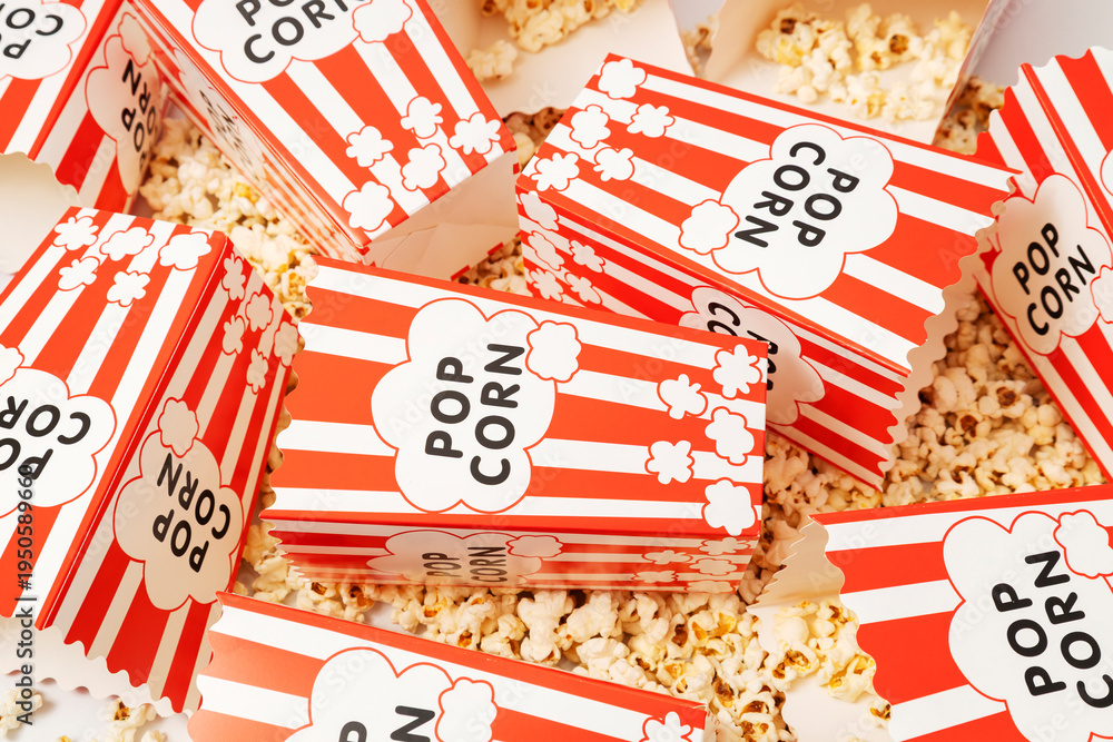 Fototapeta premium Overhead view of paper popcorn containers with striped pattern and popcorn texture background representing entertainment and leisure activity