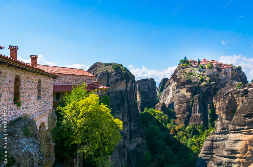 Fototapeta premium Panoramic view form The Holy Monastery of Varlaam to The Holy Monastery of Great Meteoron sitting atop sandstone pillar in Meteora, Thessaly, Greece