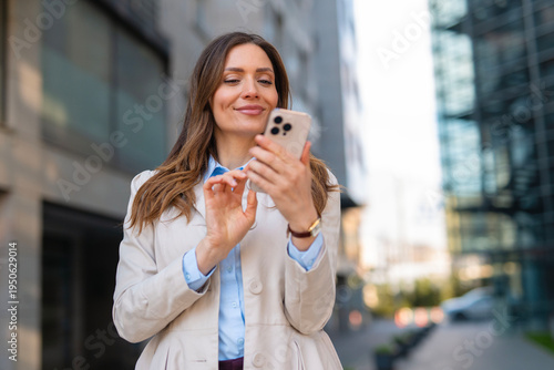 Businesswoman smiling using smartphone on urban street