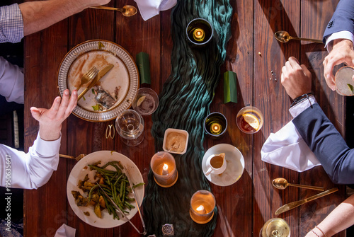 High angle detail shot of a table at a formal reception with glasses, candles, and hands.