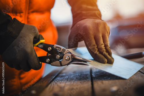Photos A man cuts a metal sheet with metal shears, construction work
