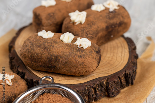 sweet brown pastry potatoes are lying on a board and paper, sweet classic cake from butter and a large amount of cocoa mixed with sponge cake and cognac, cocoa powder is scattered nearby