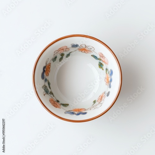 Top view of elegant porcelain bowl with delicate floral rim pattern on clean neutral background in minimalist product photography style