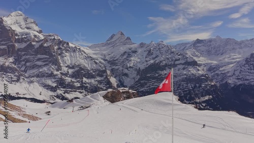 Cinematic shot of the Swiss flag with the Eiger, Monch, and Jungfrau peaks in background.