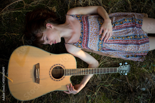 Young Woman Lying on Grass Next to Acoustic Guitar