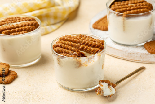 The viral two ingredient Japanese yogurt cheesecake, homemade no-bake, high-protein dessert made by inserting hard cookies into a Greek yogurt. Spoon on a Beige table.