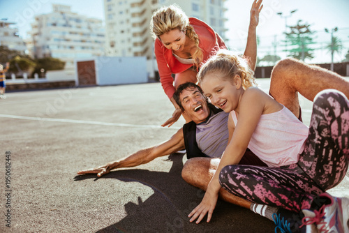 Parents and daughter laughing on urban outdoor sports court