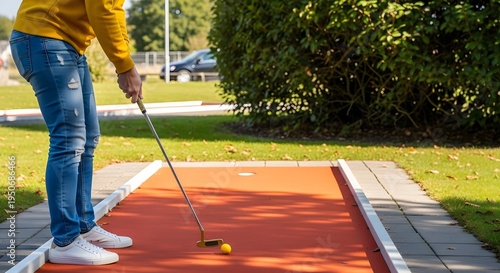Person playing mini golf on outdoor orange course