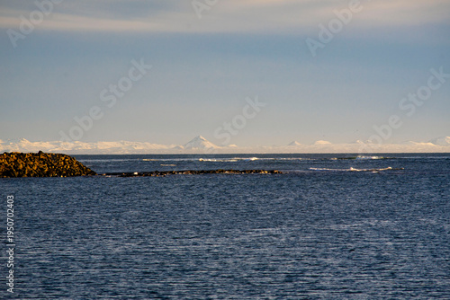 Majestic Iceland landscape with snow-capped mountain peaks on the horizon across the blue Atlantic ocean