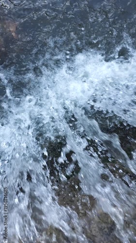 Stormwater rushing through small waterfall in urban drainage ditch in slow motion.