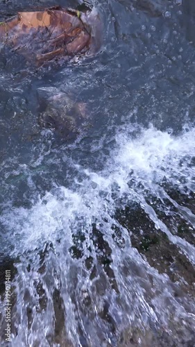 Fast flowing stormwater forming small waterfall in urban drainage channel in slow motion.