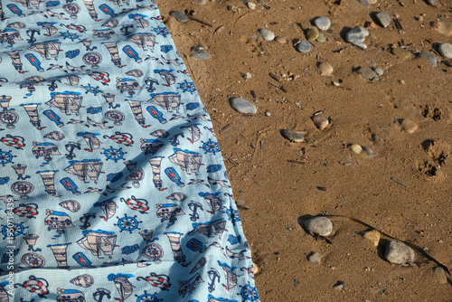Fotografi beach towel on a sandy shore with pebbles