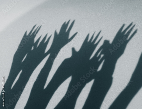 Shadows of hands reaching towards light on a flat surface during daytime