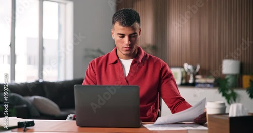 Laptop, review and man with paperwork for remote work, data entry and update records for bookkeeping. Reading, info maintenance and freelancer with pc to transcribe document, check and audit in home