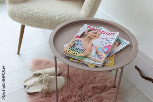 Lifestyle magazines on table and armchair indoors, closeup