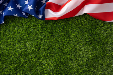 American flag draped across lush green grass background evoking patriotism and outdoor celebrations for Independence Day, Memorial Day, Fourth of July and other USA holidays