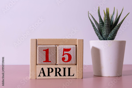 A wooden calendar with the date April 15 on the desktop.