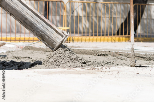 Construction workers pour wet cement onto a busy city street during daytime
