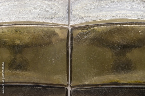 Abstract architectural detail of textured gold glass tiles with rhythmic pattern