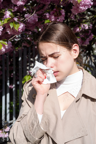 Allergy problem during spring bloom outdoors. Allergy sufferer woman with nasal congestion. Allergy symptoms with tissue and sneezing female. Allergy healthcare concept with pollen exposure.
