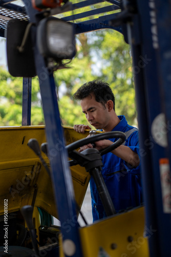 Mechanic repairing forklift engine in blue uniform