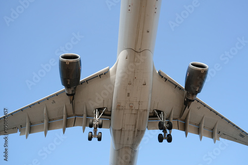 Photography Large passenger airplane flies low overhead with landing gear fully extended