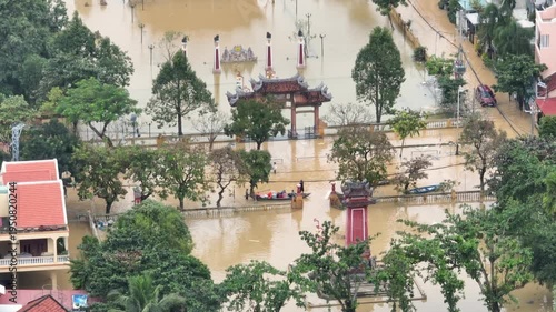 In Hoi An, Vietnam, floodwaters inundate streets and buildings. People navigate the high water in boats, showing the impact of the natural disaster.