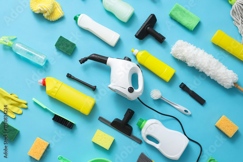 Steam cleaner with supplies on blue background, top view