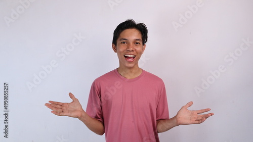 excited handsome asian young man gestures with both hands wide open with isolated white background. welcome gesture, welcoming