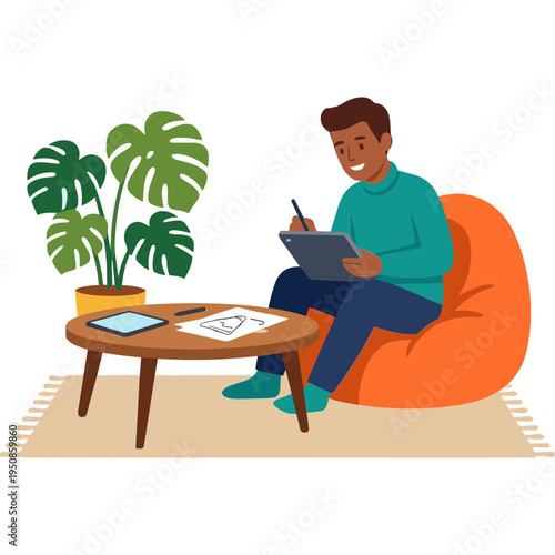 A man sits on a bean bag chair, writing on a tablet next to a plant on a coffee table indoors.