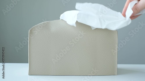 A hand pulls paper napkins out of box.