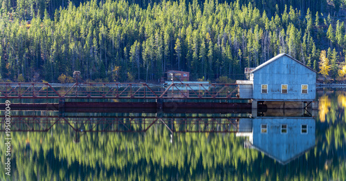 Calm Lake Reflection with Rustic Bridge and Boathouse in Forest, Montana