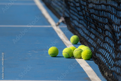 Tennis balls near net on blue court, ready for play