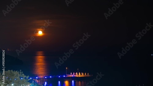 Timelapse Moonlight Over Sea Waves Full Moon Glow ocean waves on sandy beach at night wooden pier. The moon illuminates water surface. Concept of beach vacation slowing down on seacoast. Travel