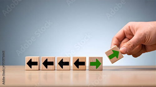 A hand places a green arrow block, symbolizing innovation, a new direction, and breaking the pattern for progress