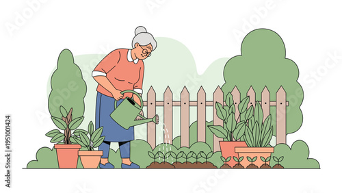 Caring elderly woman watering young plants in her backyard garden with a green watering can next to a wooden fence and leafy bushes.